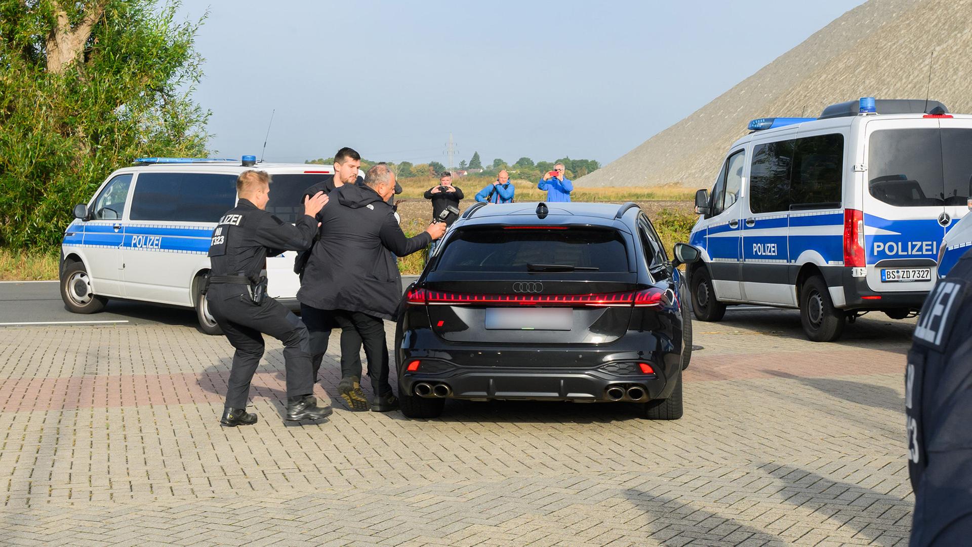 Polizisten stoppen einen Fotografen, als ein schwarzer Audi in Begleitung von Fahrzeugen der Polizei die Justizvollzugsanstalt Sehnde verlässt. | dpa/Julian Stratenschulte