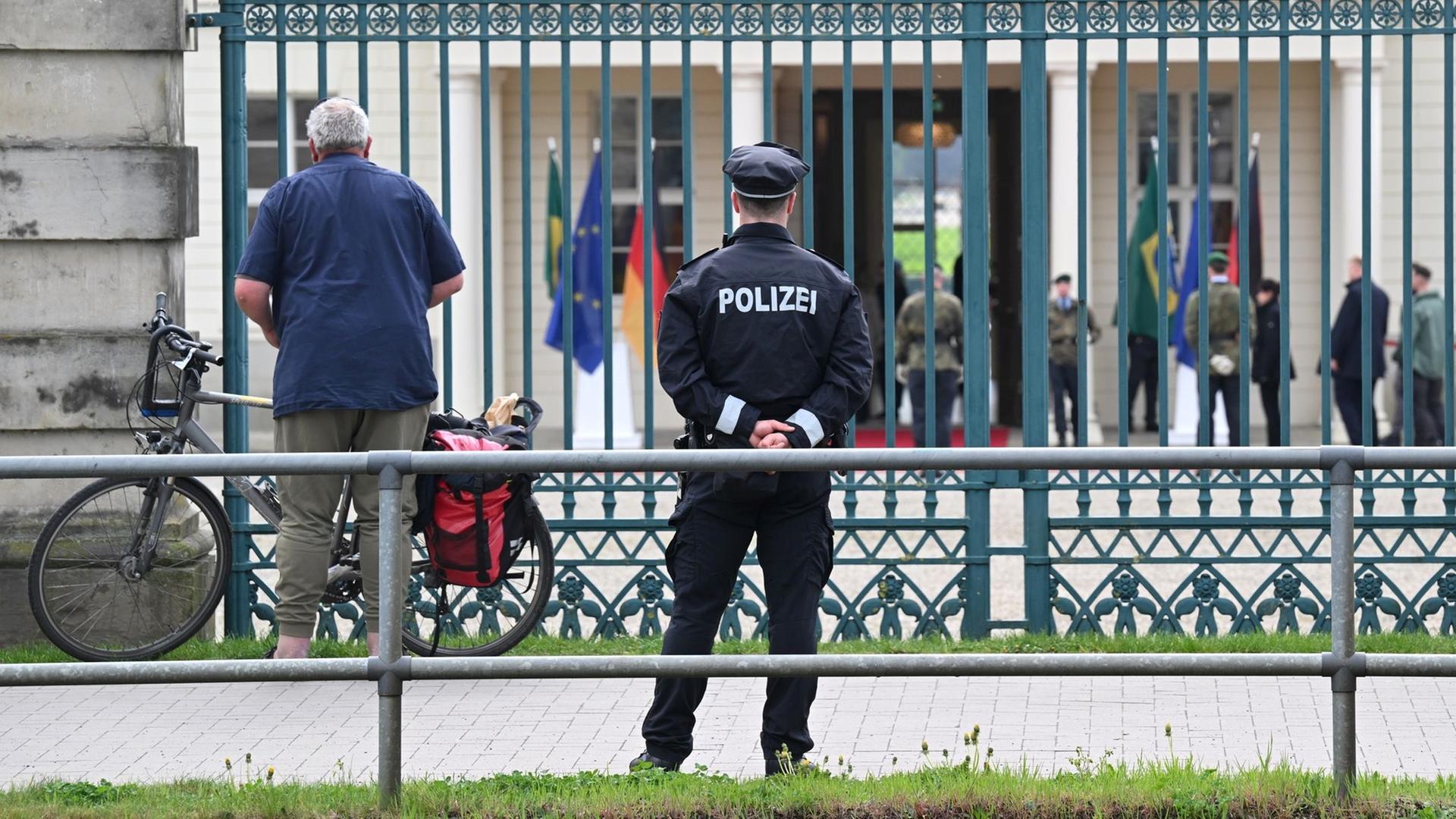 Ein Polizist steht vor einem Zaun von Schloss Herrenhausen in Hannover. | dpa-Bildfunk, Julian Stratenschulte