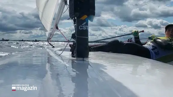 Eine Seglerin steuert ihr Boot.