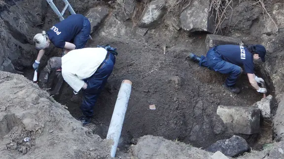 Das Polizeibild zeigt Beamte, die nach Beweisstücken graben.