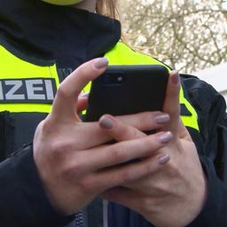 Eine Polizistin hält ein Smartphone in den Händen.