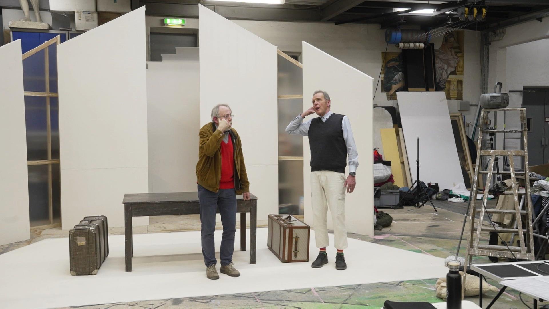 Zwei Männer auf einer Theaterbühne. | Screenshot