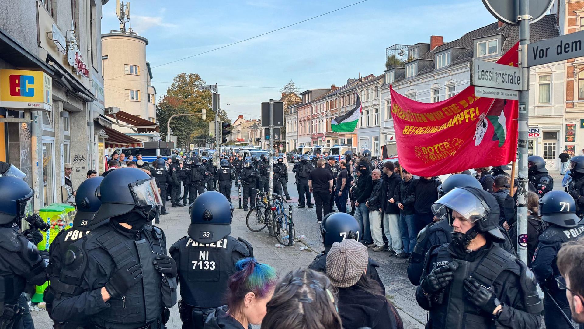 Polizisten stehen um Teilnehmer einer Versammlung gegen Militarismus und Kriegstreiberei am Rande der Feierlichkeiten zum Tag der Deutschen Einheit. | Lennart Stock/dpa