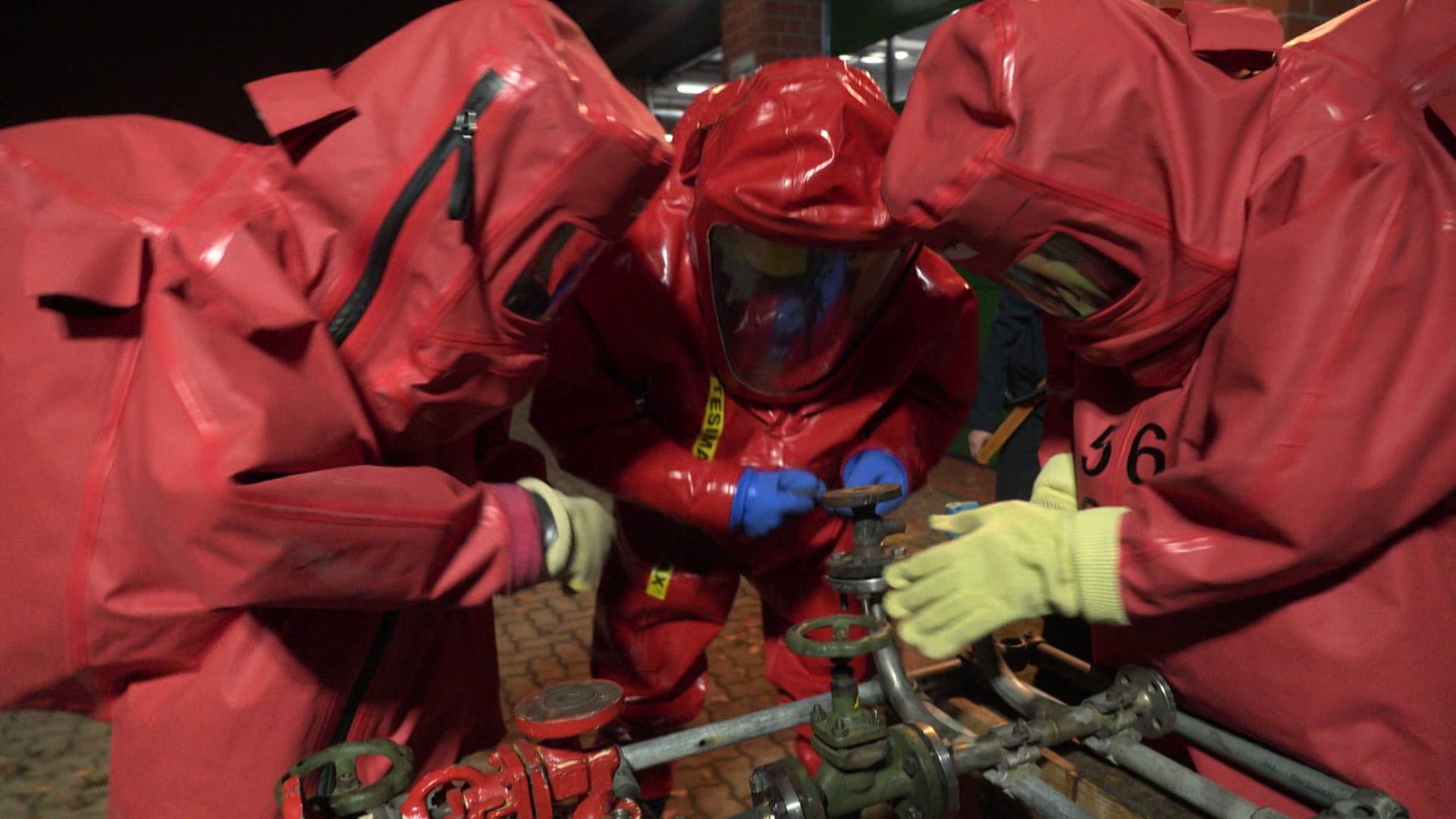 Drei Personen in roten Anzügen schrauben am Gewinde | Petra Bode