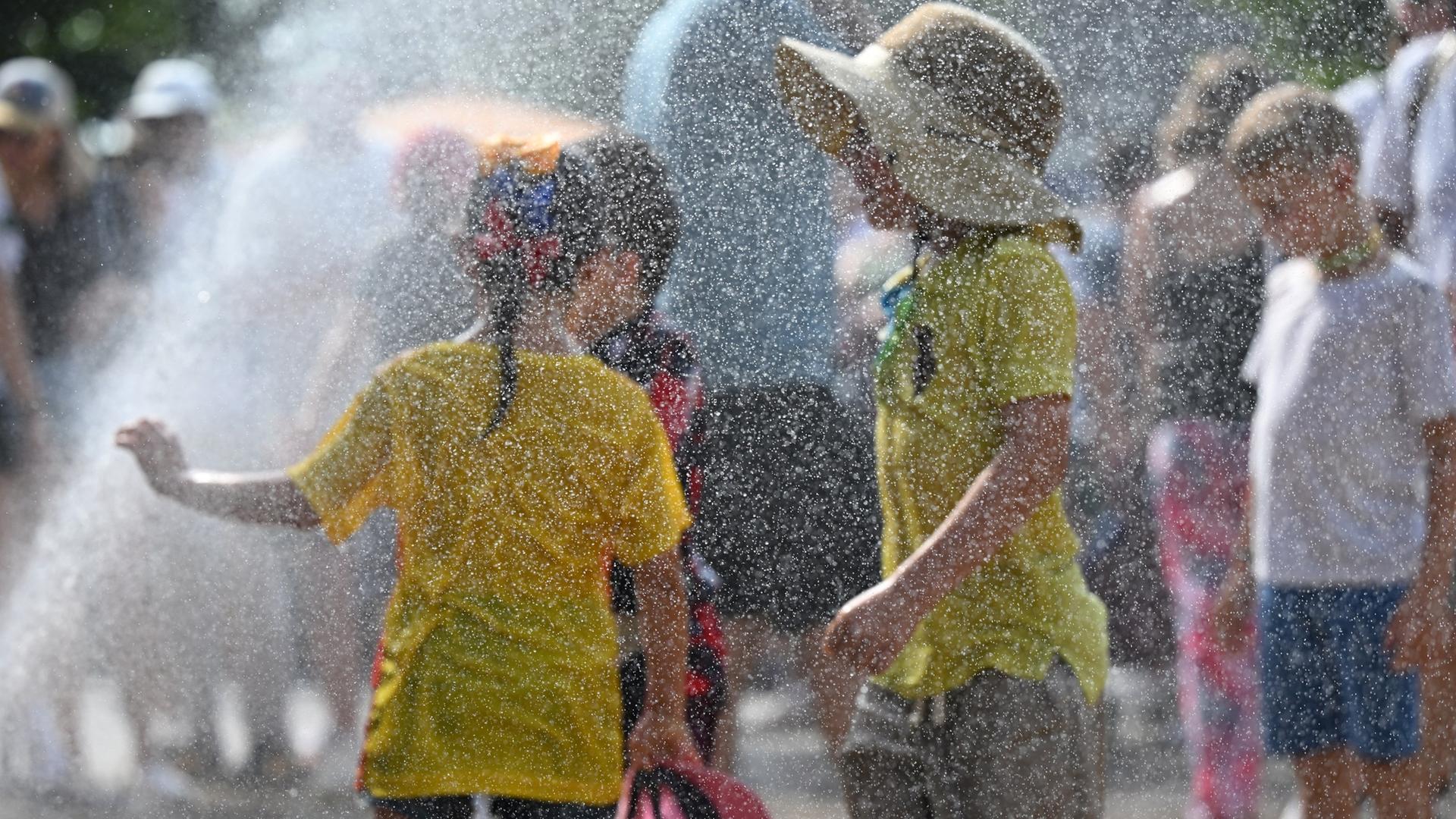 Kinder kühlen sich an einem Wassersprenger ab | picture alliance/Sven Hoppe