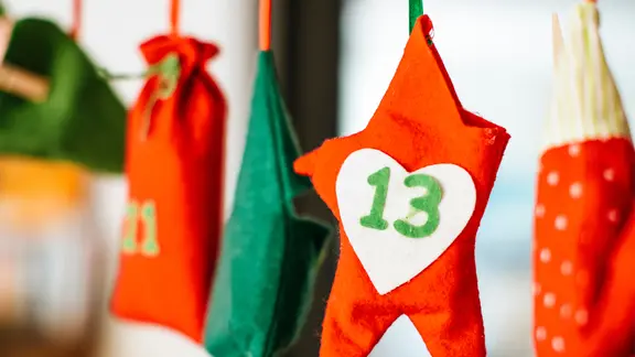 An einer Schnur, die quer durch eine Raum gespannt ist, hängen bunte Päckchen.