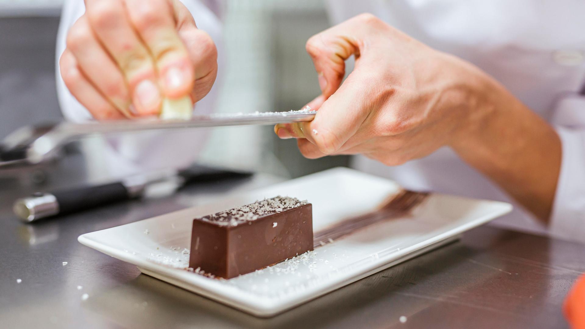 Die Aufnahme zeigt zwei Hände in Nahaufnahme, die ein Dessert vorbereiten. | picture alliance / Westend61 | DREAMSTOCK1982