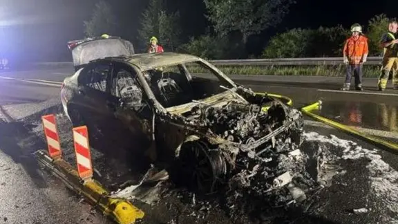 Ein ausgebranntes Elektroauto steht auf einer Straße