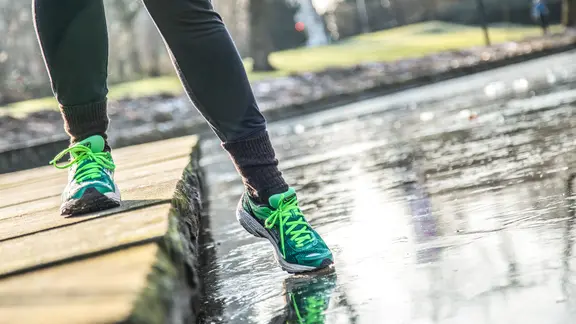 Eine Person mit Turnschuhen testet eine Eisfläche.