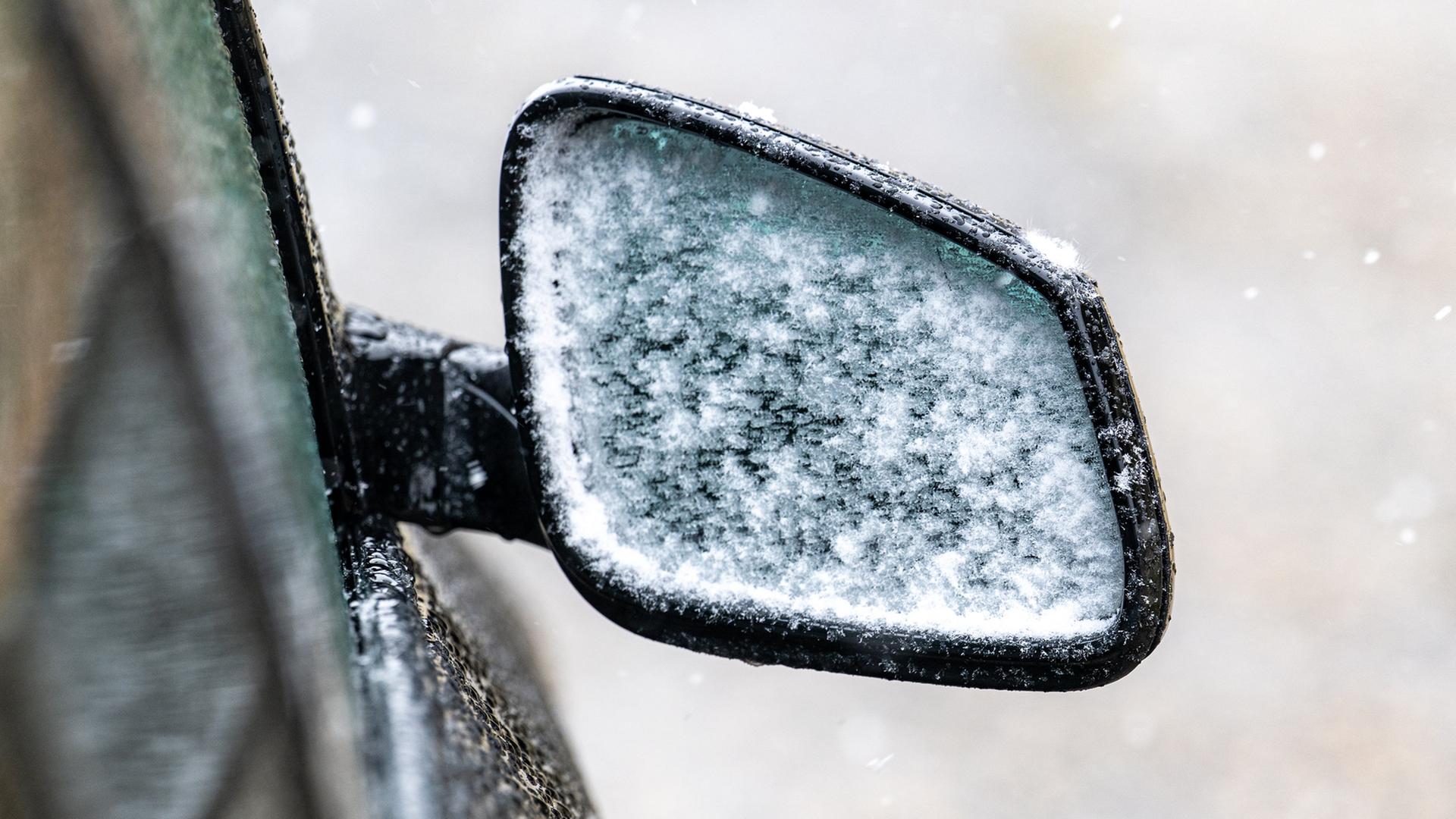 Schnee haftet am Außenspiegel eines Autos. | Armin Weigel/dpa