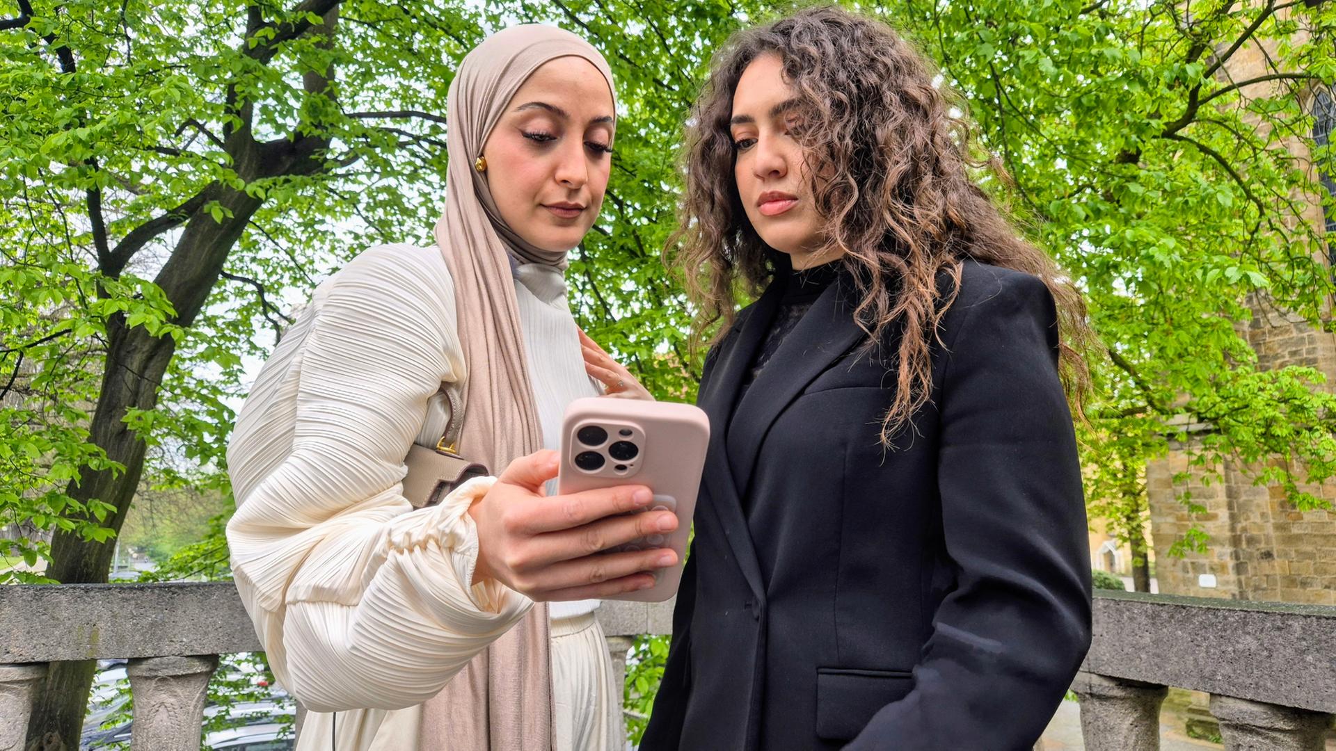 Büsra Sayed (links) hält ein Handy in der Hand, daneben steht eine Freundin. | NDR, Britta Nareyka