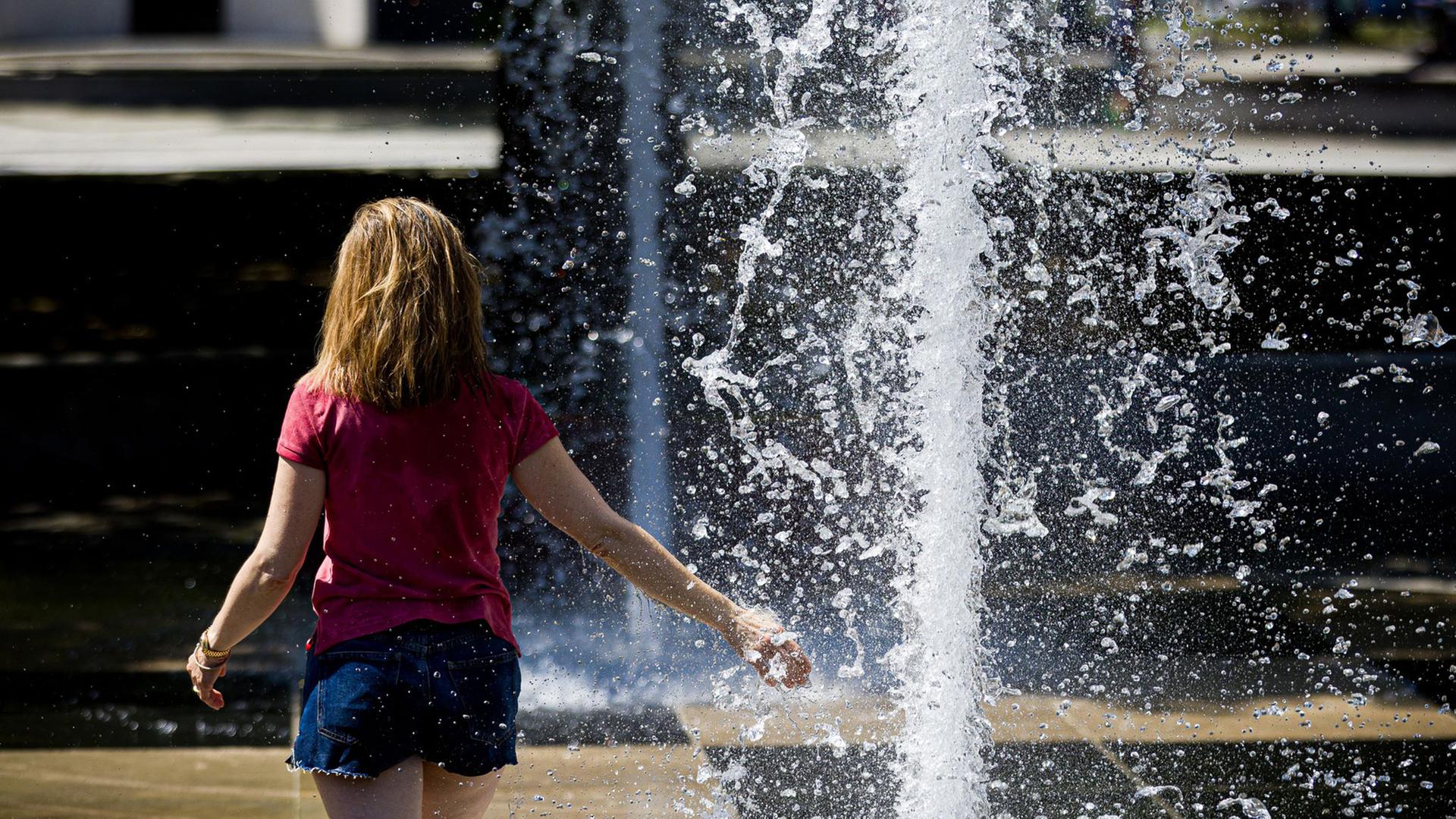 Hitzewelle: Eine Frau am Klaus-Bahlsen-Brunnen auf dem Platz der Menschenrechte in Hannover. | picture alliance/dpa-Bildfunk, Moritz Frankenberg