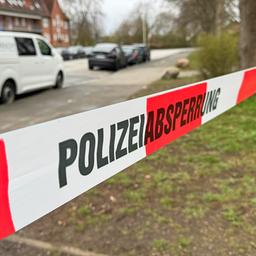 Ein rot-weißes Flatterband mit dem Schriftzug Polizeiabsperrung hängt zwischen Bäumen in Kiel-Elmschenhagen.