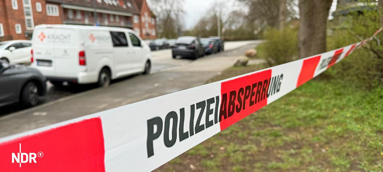 Ein rot-weißes Flatterband mit dem Schriftzug Polizeiabsperrung hängt zwischen Bäumen in Kiel-Elmschenhagen. | NDR, Tobias Gellert Ein rot-weißes Flatterband mit dem Schriftzug Polizeiabsperrung hängt zwischen Bäumen in Kiel-Elmschenhagen.