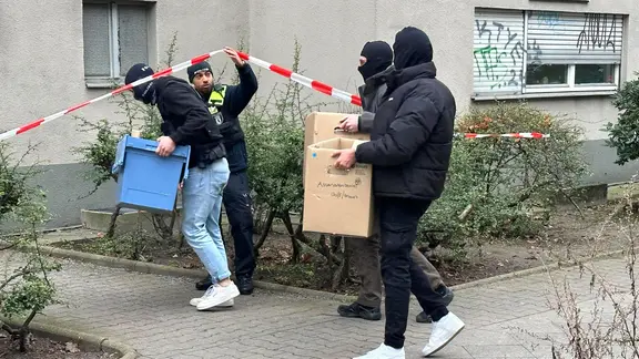 Ermittler gehen mit Kisten und Kartons in das Wohnhaus der früheren RAF-Terroristin Daniela Klette.