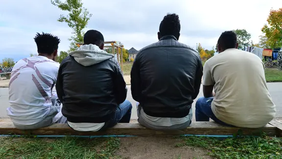 Vier junge Männer aus Eritrea sitzen in Saalfeld (Thüringen) vor einer Flüchtlingsunterkunft.