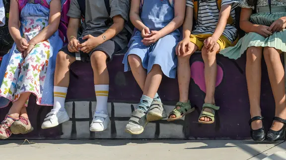 Schulkinder sitzen auf einer Bank. | picture alliance / Winfried Rothermel, Winfried Rothermel Schulkinder sitzen auf einer Bank.