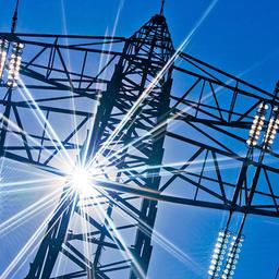 Ein Strommast mit Sonnenstrahlen und blauem Himmel im Hintergrund.