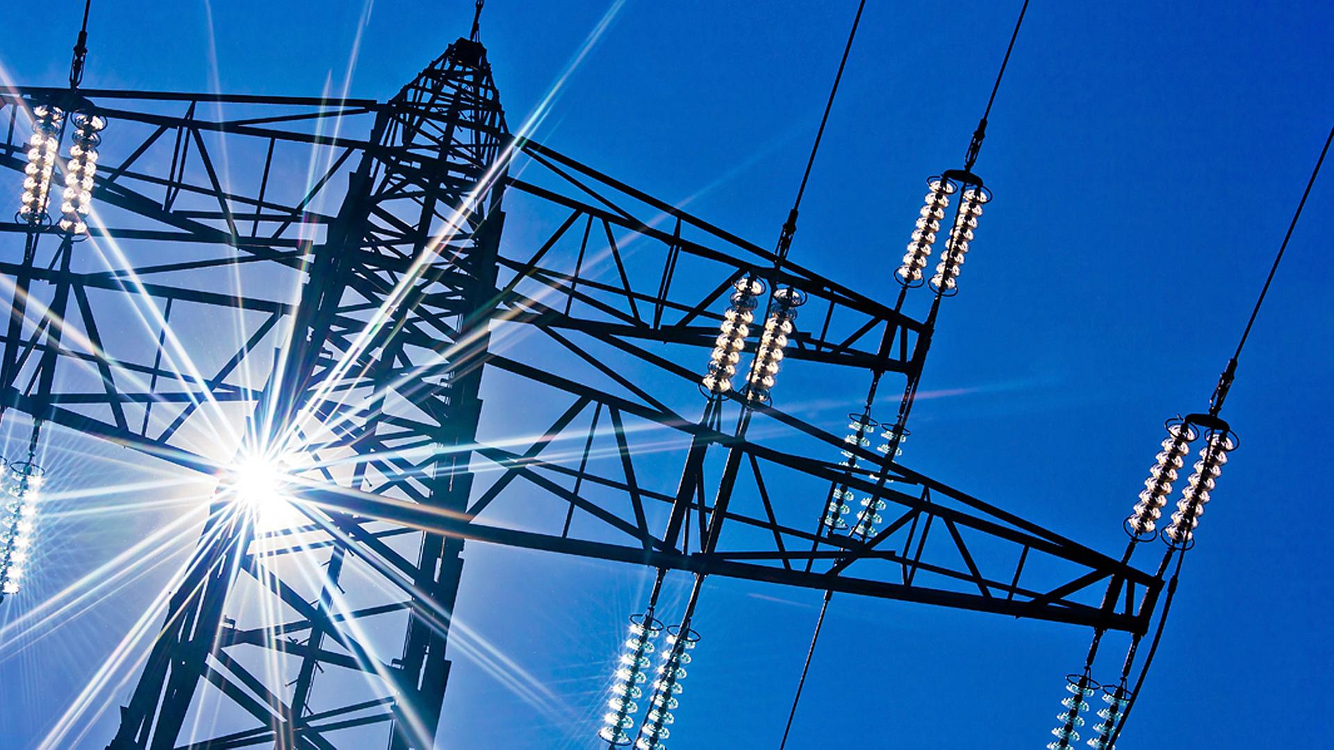 Ein Strommast mit Sonnenstrahlen und blauem Himmel im Hintergrund. | Fotolia.com, Gina Sanders