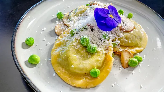 Erbsen-Bärlauch-Ravioli mit Champignons und Schafskäse auf einem Teller angerichtet