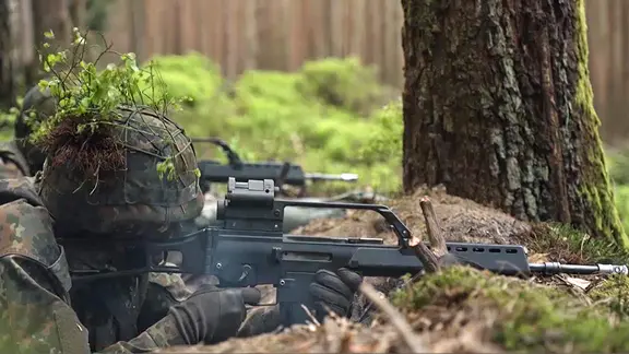 Soldaten der Bundeswehr liegen in einem Wald und schießen.