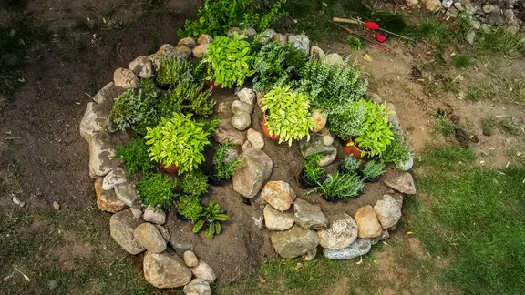 Eine bepflanzte Kräuterspirale aus Feldsteinen