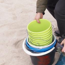 Am Strand der Ostsee werden Eimer zum Sammeln von Müll verteilt.