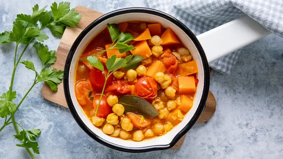 Ein Topf mit einem Eintopf aus Kichererbsen, Süßkartoffeln und Tomaten.