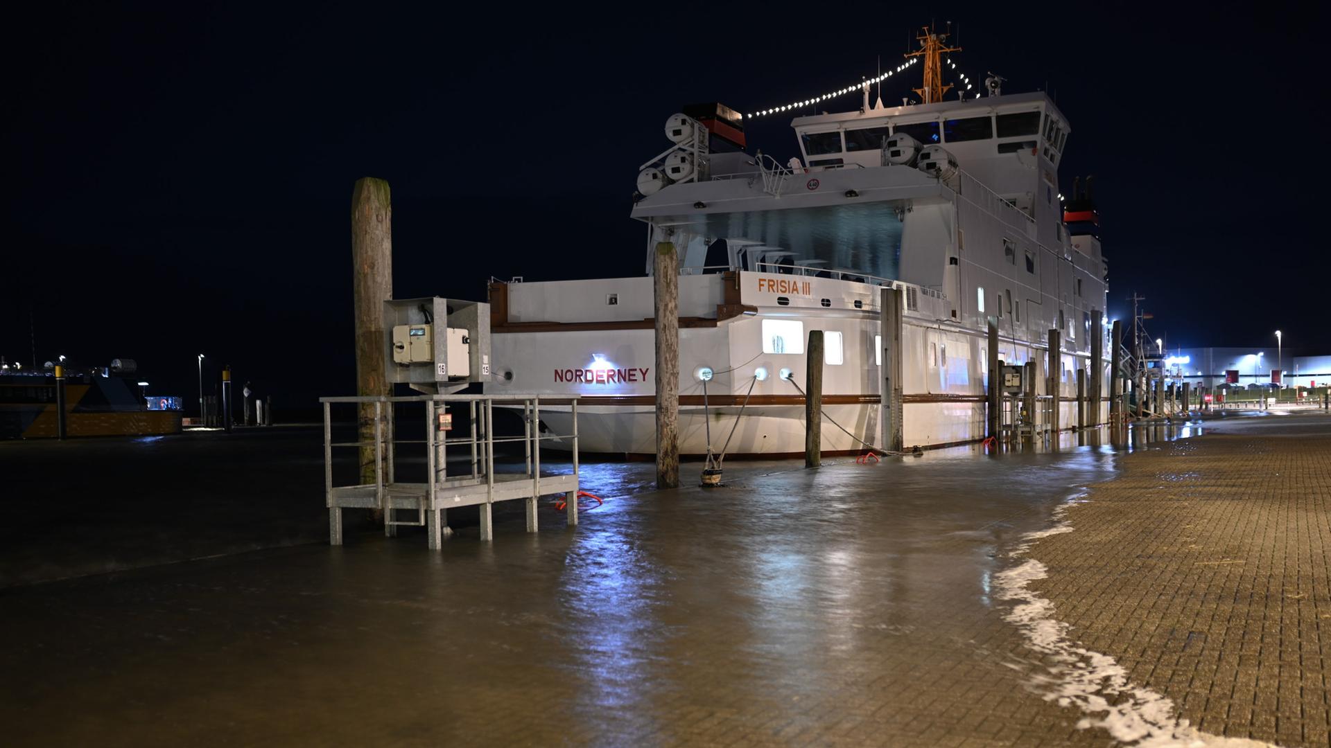 Das Wasser ist im Hafen von Norddeich über die Kaimauer gelaufen, die Norderney -Fähre liegt sicher vertaut.  | picture alliance/dpa | Lars Penning