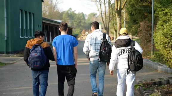 Vier geflüchtete junge Männer laufen in Hamburg eine Straße entlang.