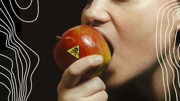 Eine Frau beißt in einen Apfel mit einem gelben Warnsticker.