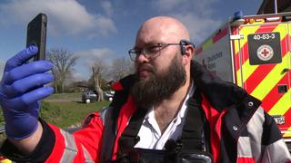 Telemedizin für den Notfall proben: Ein Sanitäter bei einer Übung mit einem Handy in der Hand.