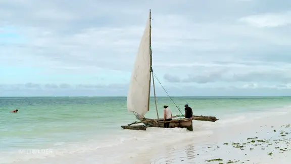 Zwei Männer schieben in ein Boot ins Wasser.