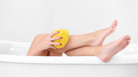 Weibliche Beine in der Badewanne.