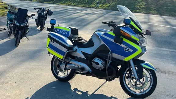 Ein Motorrad der Polizei steht bei einer Kontrolle vor drei privaten Motorrädern.