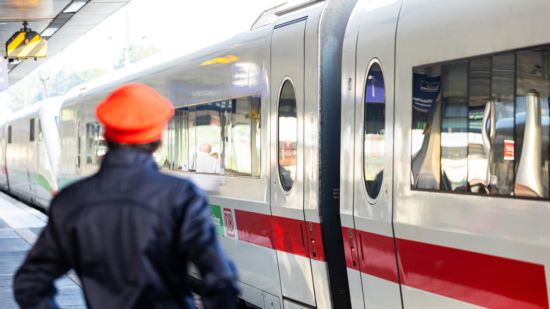 Ein Mitarbeiter der Deutschen Bahn (DB) steht neben einem ICE-Zug an einem Gleis im Hauptbahnhof Hannover. | picture alliance/dpa/Michael Matthey, Michael Matthey