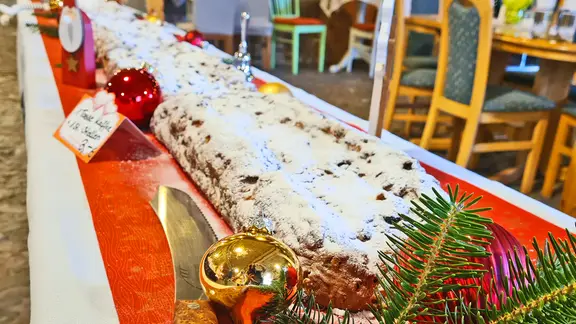 Traditionell wird auf dem Markt ein mehrerer Meter langer Stollen angeschnitten und verkostet. | Feldsteinscheune Bollewick Ein riesiger Stollen auf einem Tisch in der Feldsteinscheune Bollewick.