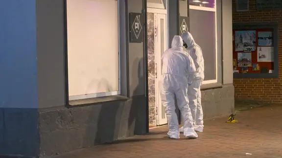 Die Ermittlungen zu dem Fall hat die Kriminalpolizei übernommen. | Florian Sprenger Zwei Polizisten stehen in Schutzkleidung am Tatort in der Fußgängerzone.