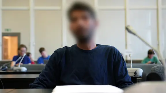 Ein Mann sitzt in einem Gerichtssaal in Hamburg. Er soll sein Kind entführt und den Flugbetrieb am Hamburger Flughafen stundenlang lahmgelegt haben.