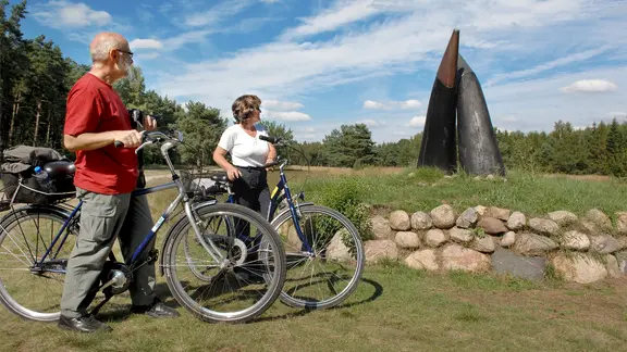 Zwei Radfahrer stehen in Kropp vor den berühmten Ochsenhörnern, die auf dem Radfernweg Ochsenweg liegen.