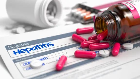 Hepatitis B: Diagnose Hepatitis steht auf einem Zettel. Daneben liegen Tabletten und ein Tablettenfläschchen.