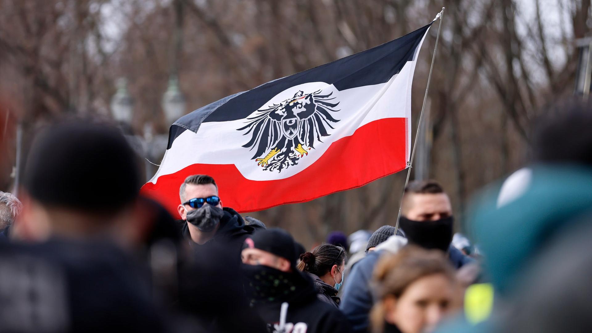 Teilnehmer auf einer Demonstration von Rechtsextremen und Reichsbürgern halten eine Fahne, die an die Reichsflagge erinnert. | picture alliance/Geisler-Fotopress, Jean MW/Geisler-Fotopress