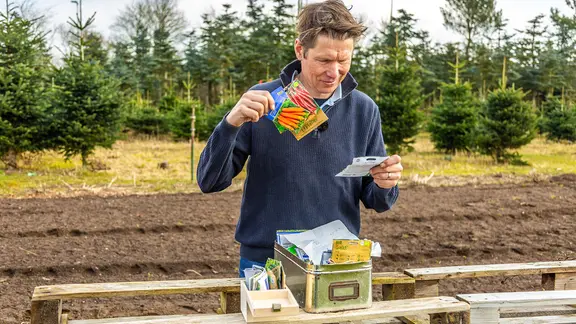 Gärtner Peter Rasch schaut sich verschiedene Tüten mit Saatgut an.
