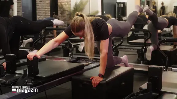 Eine junge Frau beim Ganzkörpertraining Reformer-Pilates.