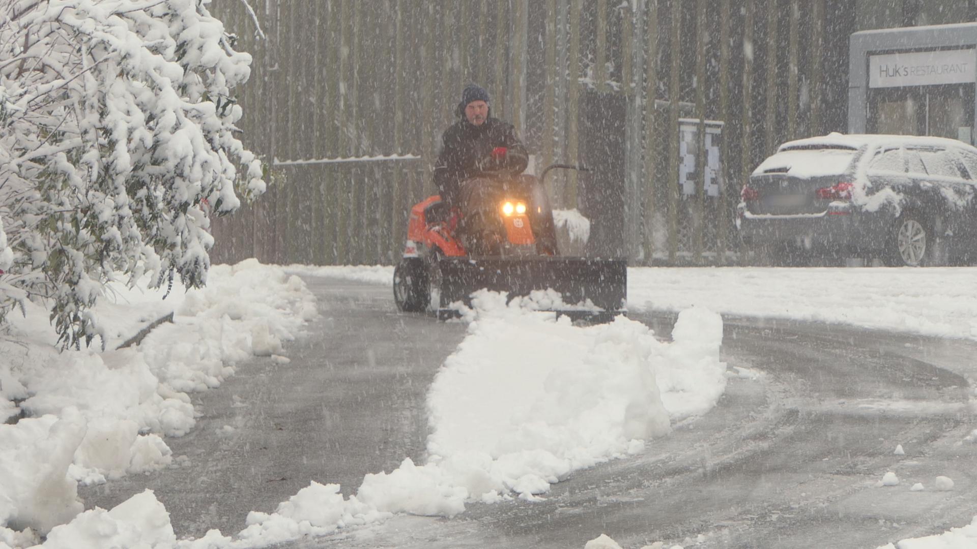 Eine Person fährt in Aschberg mit einem Schneeschieber über die Straße. | Daniel Friedrichs