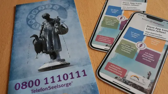 Eine Broschüre und Flyer weisen auf die Telefonseelsorge (0800) 111 01 11 hin.