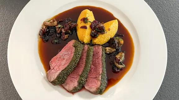 Reh mit Ras-el-Hanout-Kruste und Kürbis-Couscous auf einem weißen Teller angerichtet.