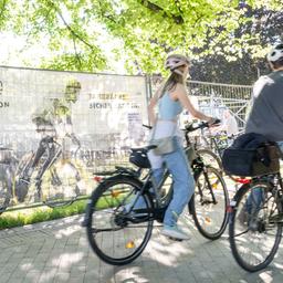Zwei Menschen fahren Fahrrad. Im Hintergrund das Banner für die Velostation der Kieler Woche.