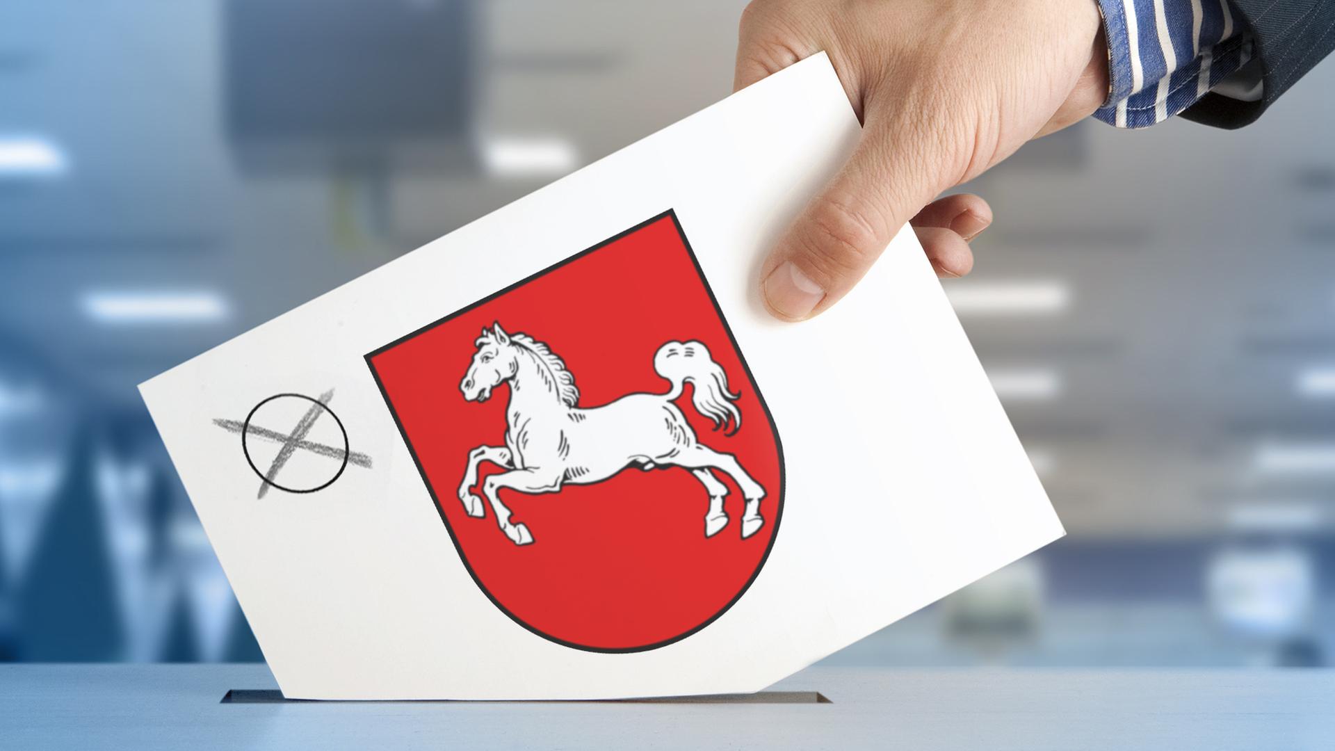 Eine Wahlkarte mit einem Kreuz und dem Wappen von Niedersachsen wird in eine Wahlurne geworfen. | fotolia.com, _AndreL