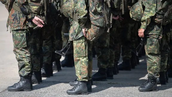 Rekruten in Uniform stehen auf einem Truppenübungsplatz.